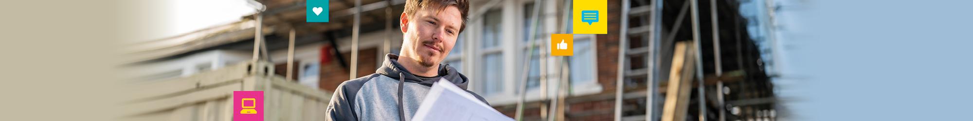 Person standing outside a house holding plans